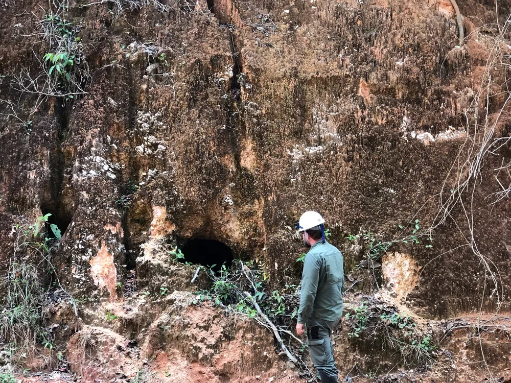 Geologist examining weathered pegmatite at mine entrance