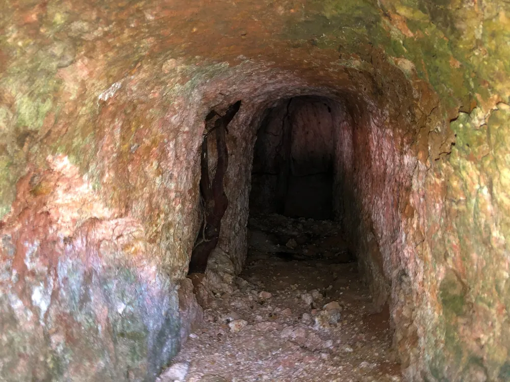 Six-metre artisanal excavation exposing a lenticular pegmatite vein.