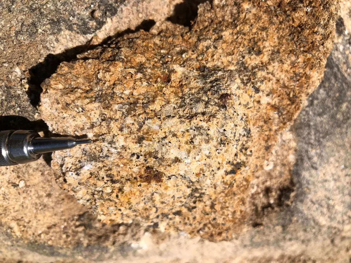 Coarse-grained granite sample showing feldspar, quartz, biotite, and minor weathering.