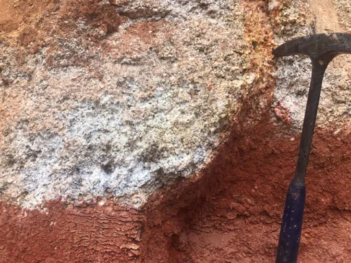 Sharp transition between red saprolitic clay and pale granitic core, showing an advanced weathering profile.