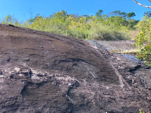 Weathered granite outcrop showing sheet-like exfoliation and faint pale vein traces.