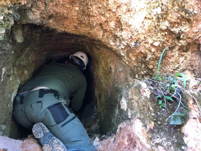 Geologist examining a small artisanal tunnel developed in weathered granitic rock.