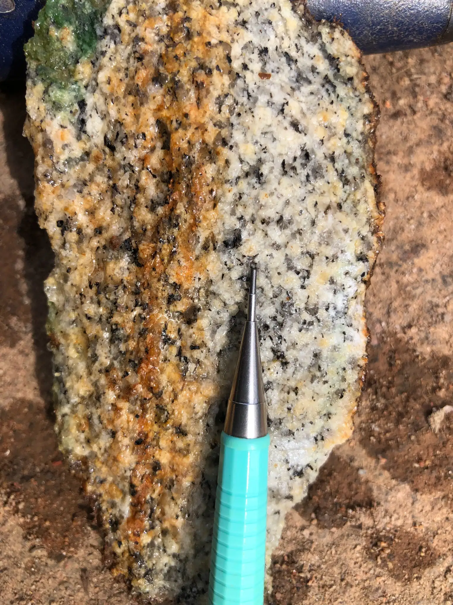 Granitic hand sample with quartz-feldspar intergrowths and iron staining.
