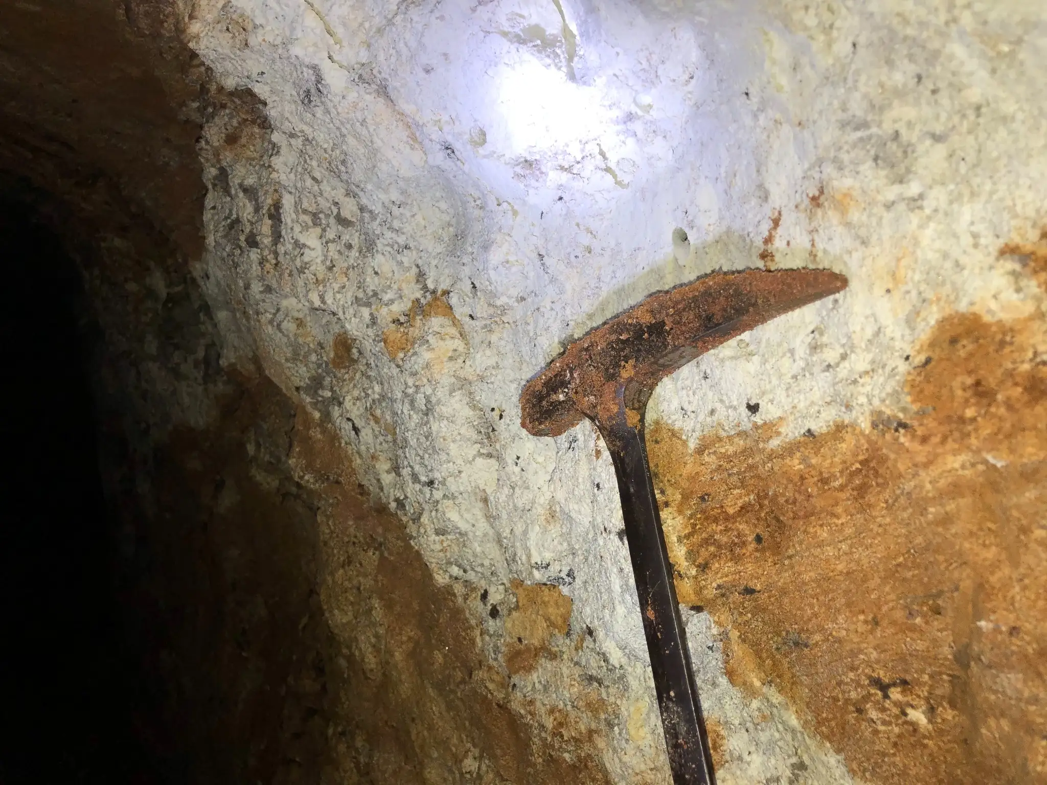 Rust-stained pegmatite wall inside an artisanal excavation