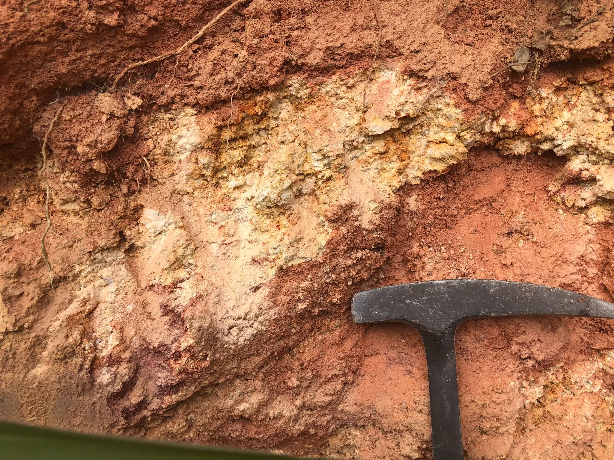 Weathered granitic saprolite with bleached feldspar and iron staining