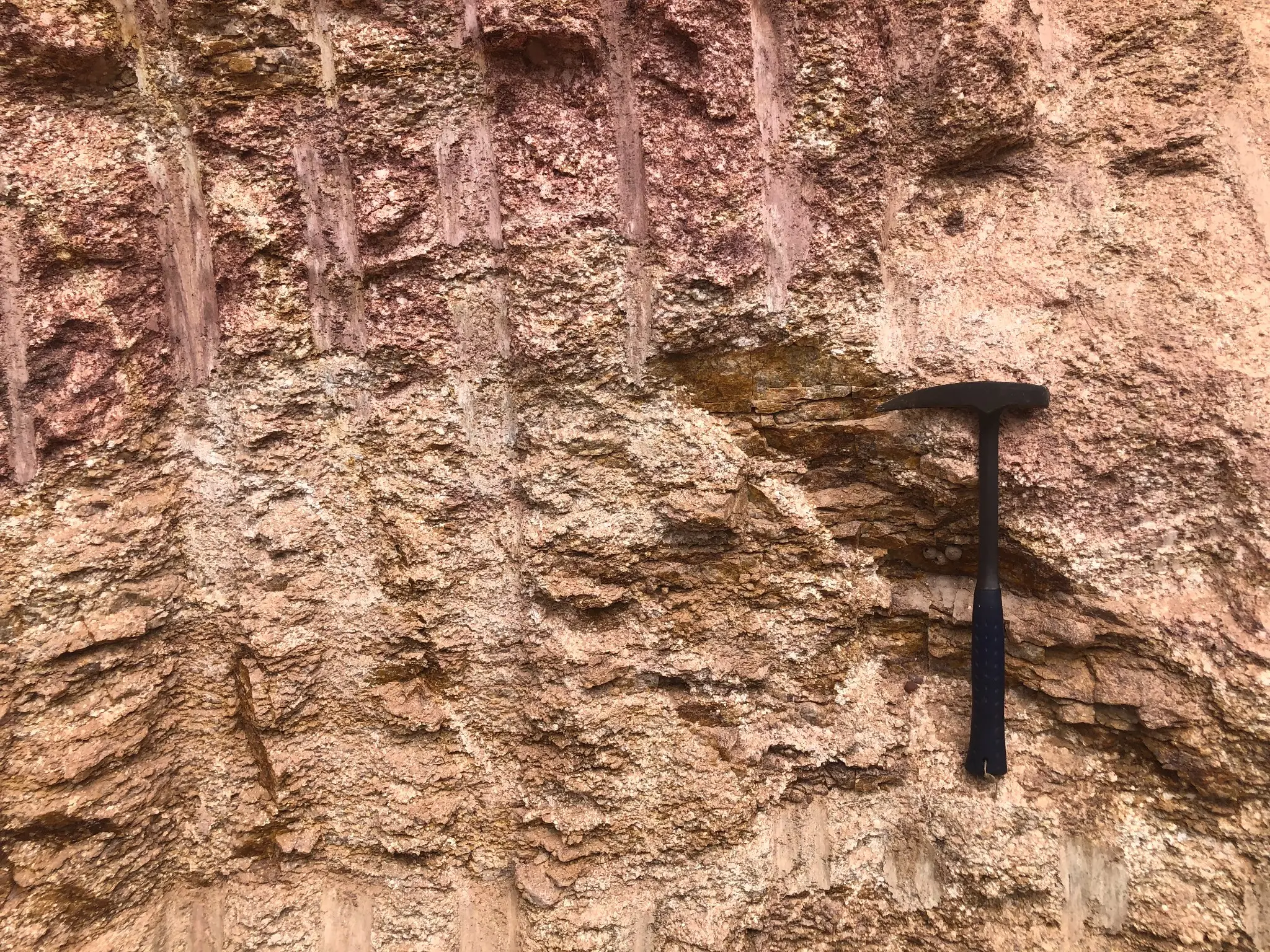 Vertical roadcut showing deeply weathered granitic saprolite with visible textural relics of the parent rock.