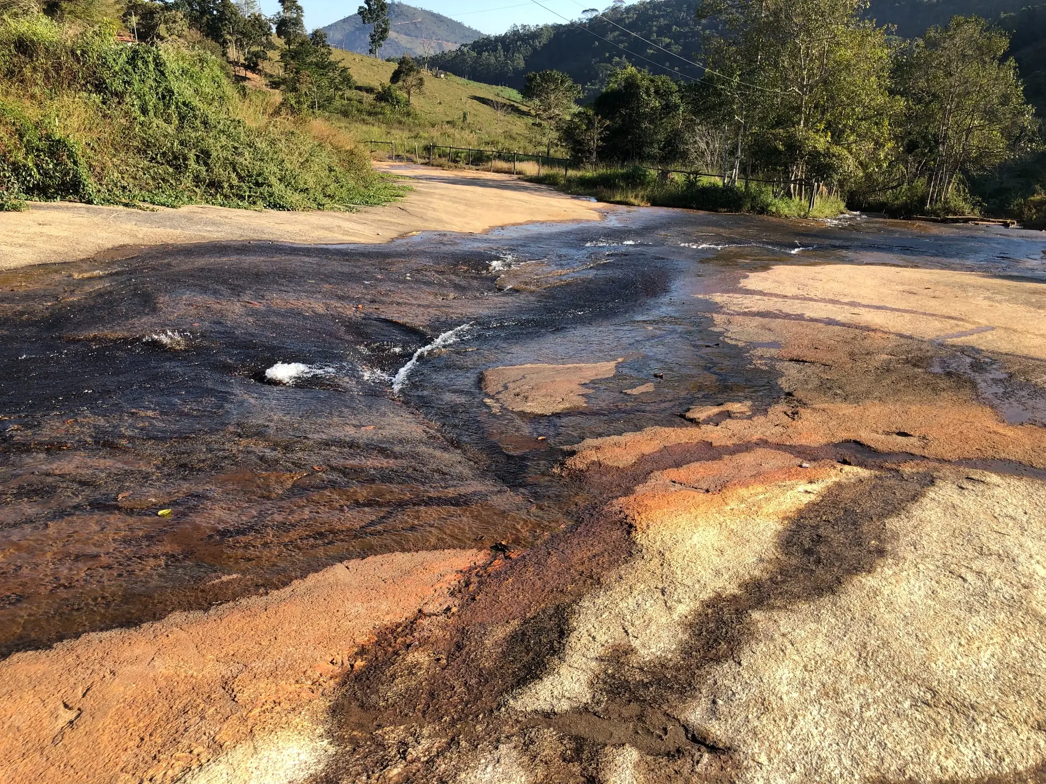 Stream flowing over weathered granite with orange-brown staining.