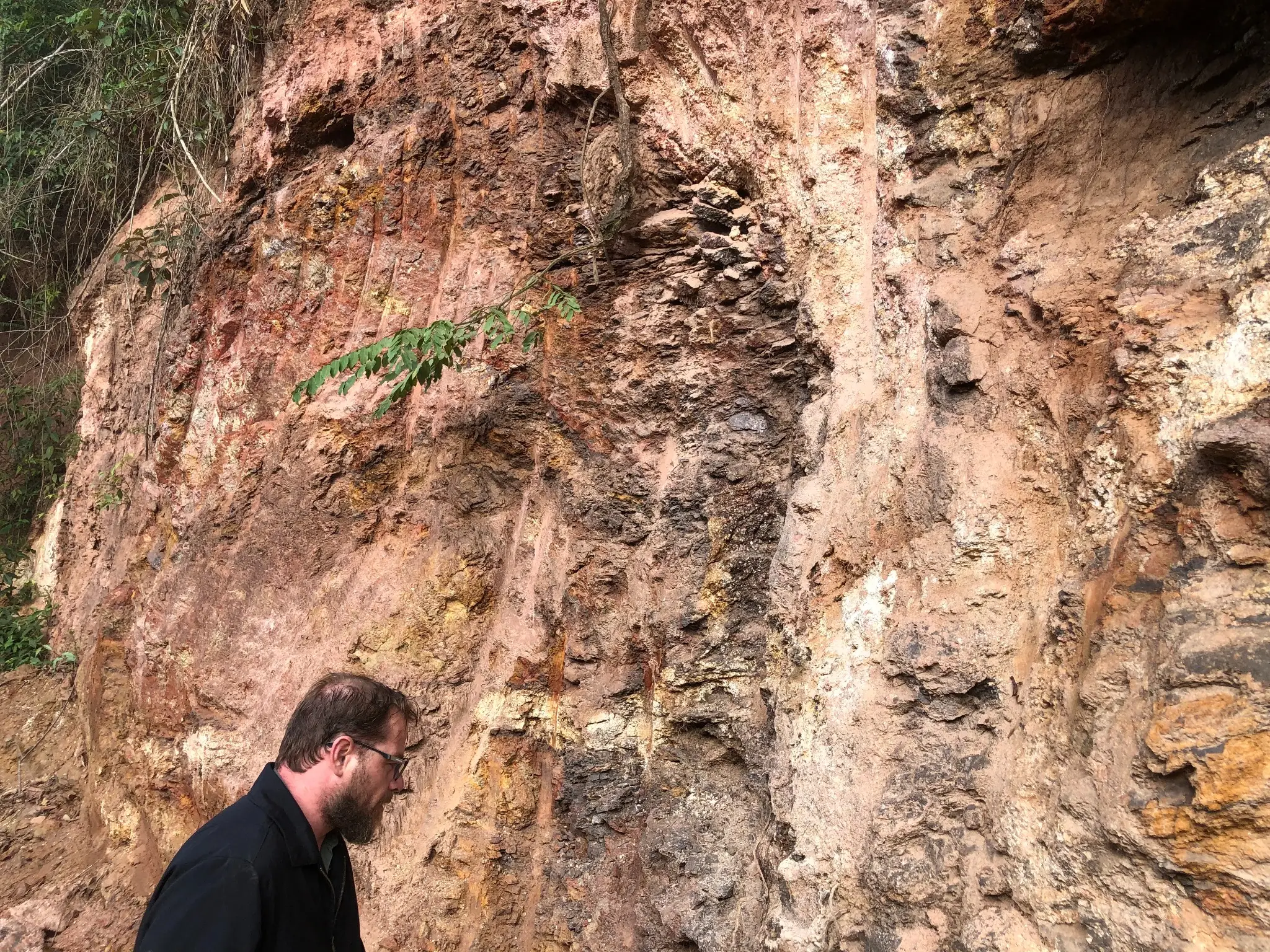 Field examination of a weathered outcrop with iron-rich bands