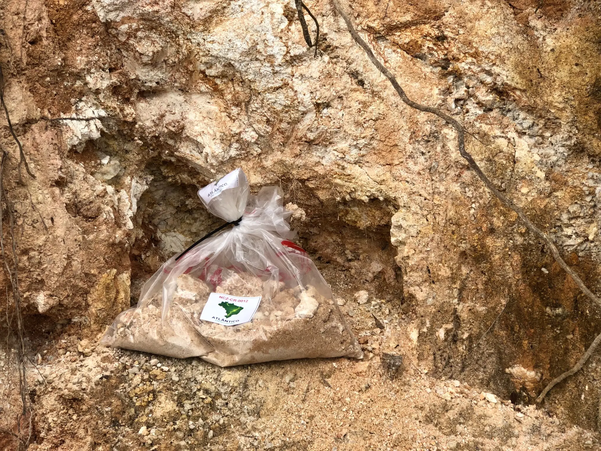 Labeled sample bag with kaolinized saprolite from a weathered granitic exposure.