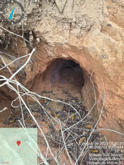 Narrow artisanal shaft opening in weathered terrain.